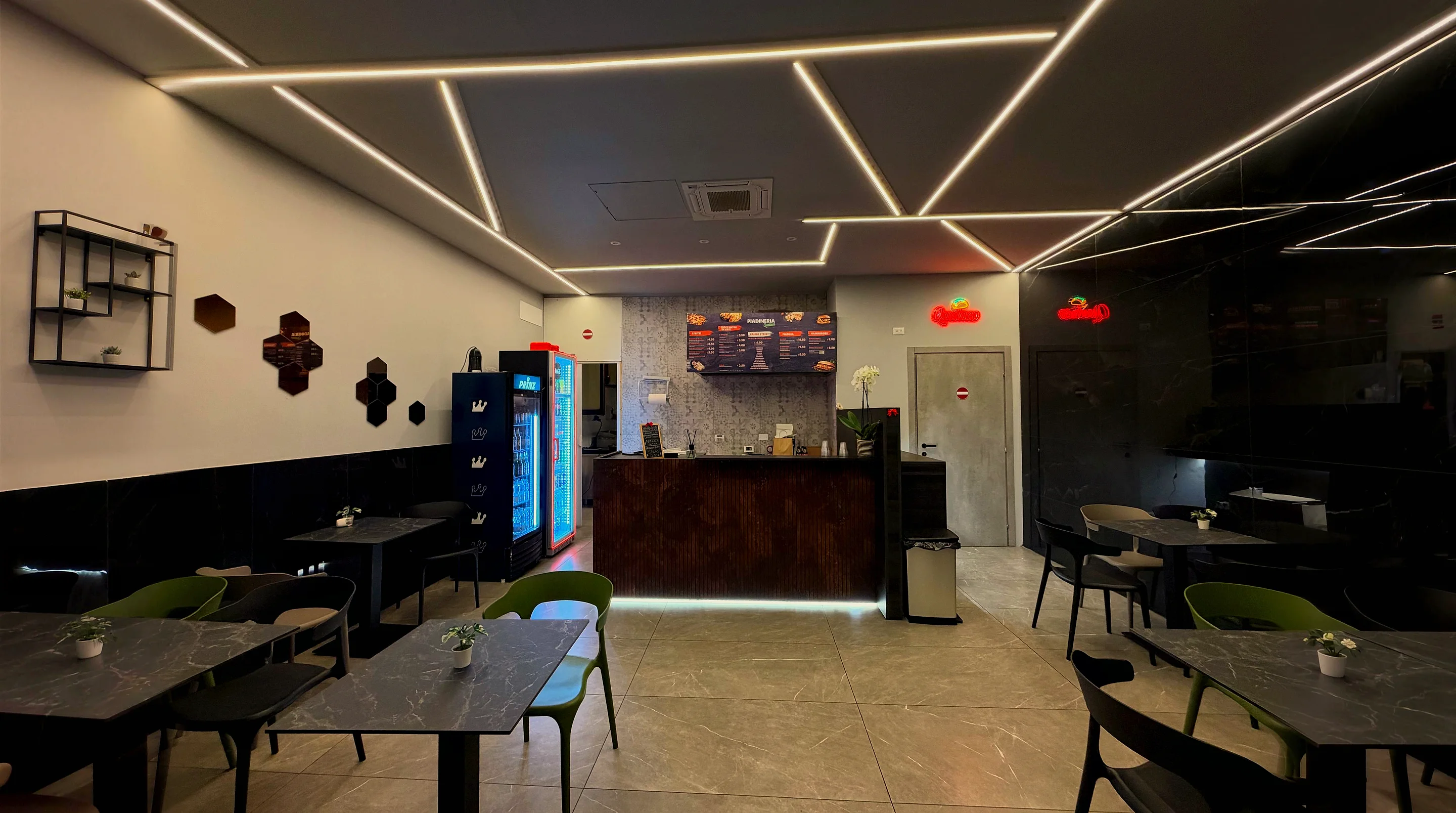 La sala di Quetaco: soffitto con le strisce LED, il bancone e i tavoli in marmo